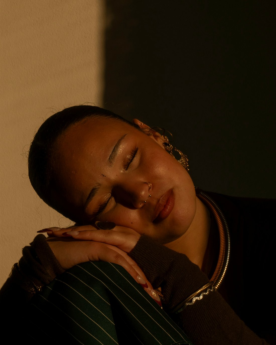 A woman resting, eyes closed, in soft warm light